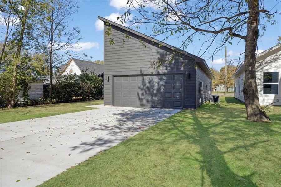 View of home's exterior featuring a garage, an outdoor structure, and a lawn