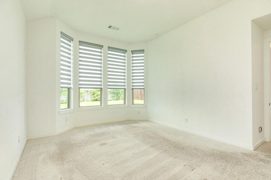 Primary Bedroom with oversized bay windows overlooking the backyard and waterfront, located conveniently adjacent to the office space.