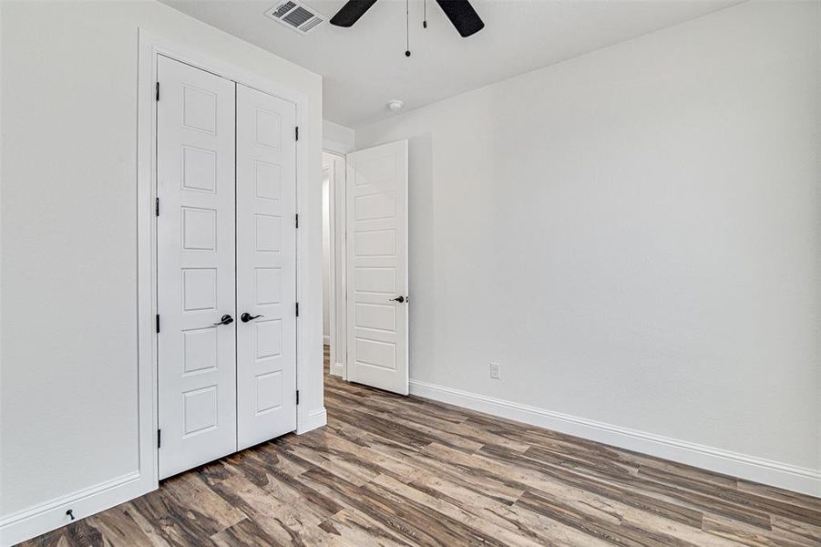 Unfurnished bedroom with a closet, hardwood / wood-style flooring, and ceiling fan