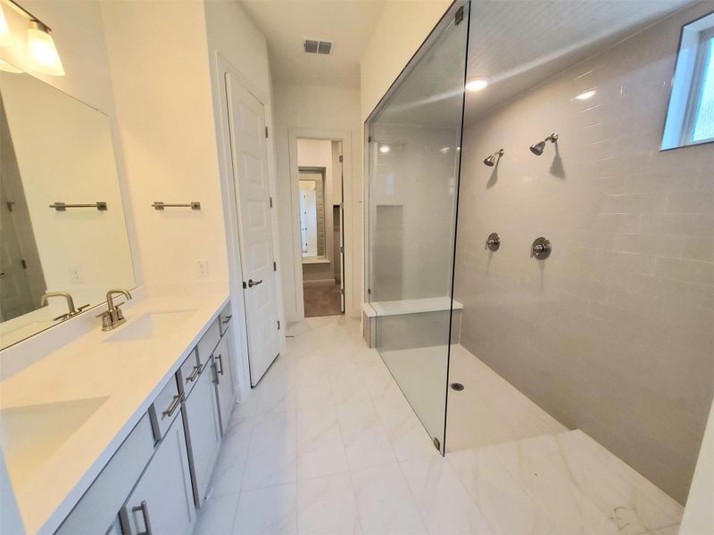 Full bath featuring double vanity, a walk in shower, visible vents, and a sink Full bath featuring double vanity, a walk in shower, visible vents, and a sink