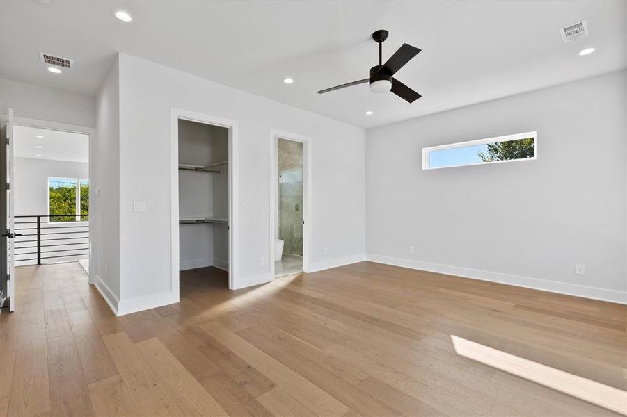 Unfurnished bedroom featuring ensuite bathroom, ceiling fan, a spacious closet, light hardwood / wood-style floors, and a closet