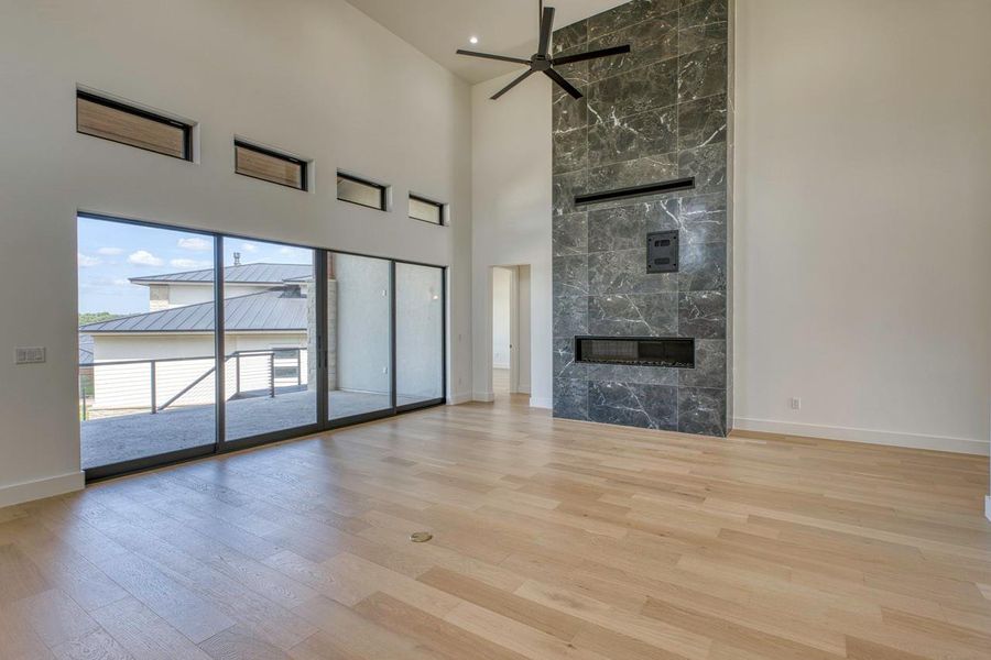 Soaring ceilings and a floor-to-ceiling stone fireplace anchor this light-filled modern living space.