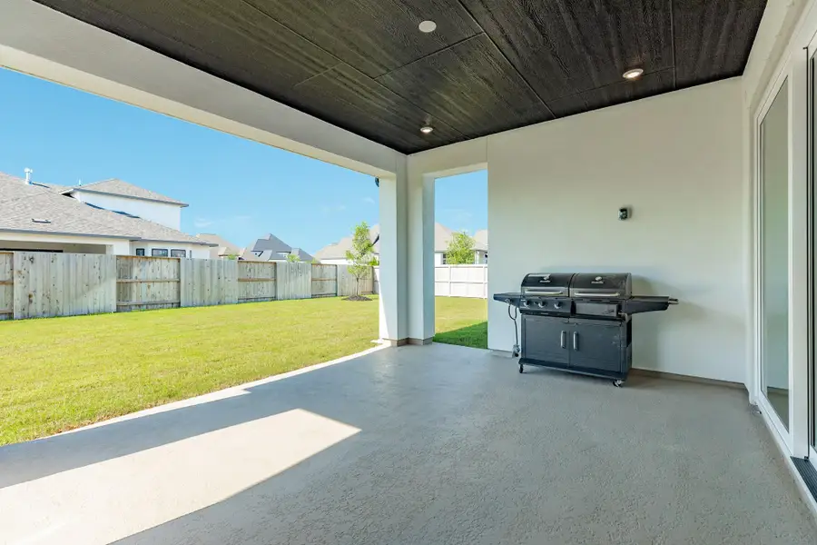 This newly constructed home, less than one year old, features an extended covered patio complete with a custom wooden ceiling and a natural gas line for the grill, ensuring a continuous fuel supply for your outdoor cooking needs.