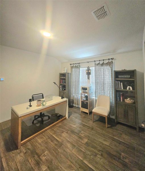 Room featuring wood-finish flooring, white walls, and a window with blinds
