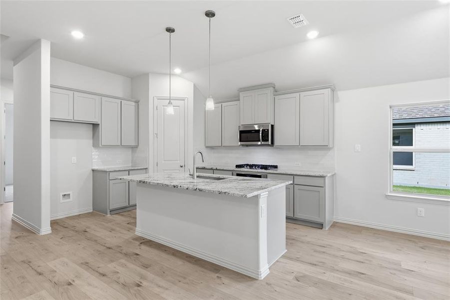 Modern kitchen featuring light wood-finish flooring, light gray cabinetry, and white subway tile backsplash Modern kitchen featuring light wood-finish flooring, light gray cabinetry, and white subway tile backsplash