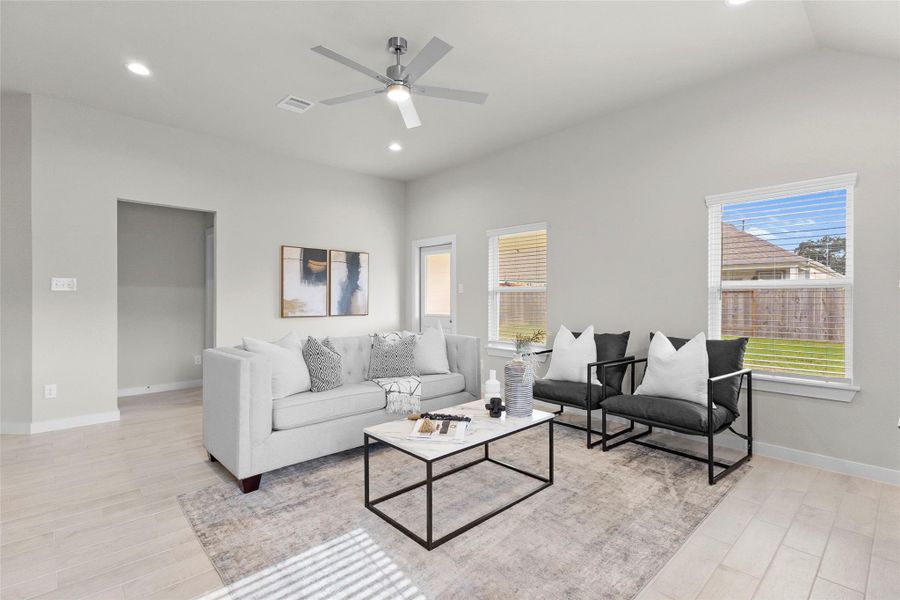 This bright, open living room offers a versatile layout with wood look flooring and oversized windows that fill the space with natural light. A modern ceiling fan and neutral tones create a comfortable, move in ready backdrop, while the flow into the adjoining hallway adds a sense of openness throughout. It's a welcoming space for both everyday living and entertaining guests. This bright, open living room offers a versatile layout with wood look flooring and oversized windows that fill the space with natural light. A modern ceiling fan and neutral tones create a comfortable, move in ready backdrop, while the flow into the adjoining hallway adds a sense of openness throughout. It's a welcoming space for both everyday living and entertaining guests.