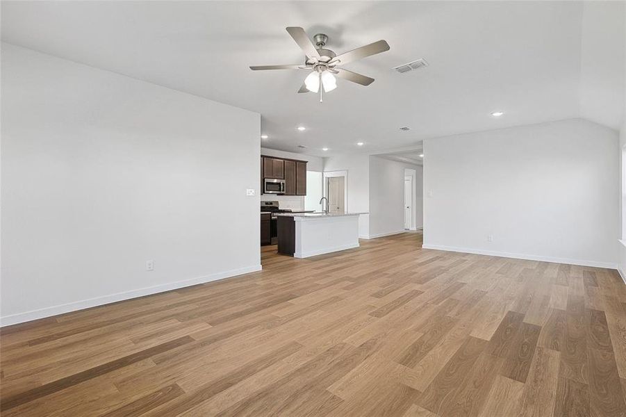 Unfurnished living room with light hardwood / wood-style flooring, sink, and ceiling fan