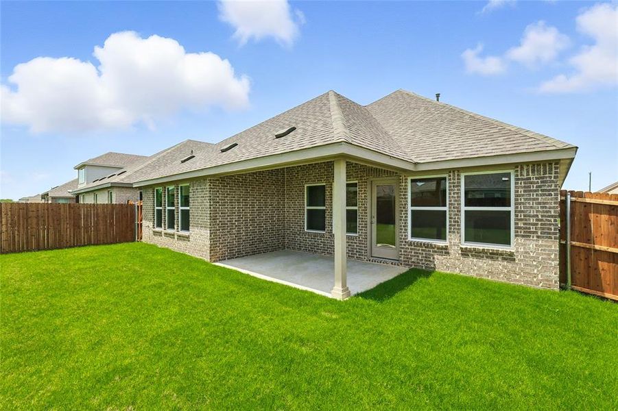 Rear view of property with brick siding, roof with shingles, and a patio area