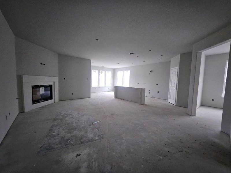 Spacious interior featuring an open layout, a contemporary fireplace with a white surround, multiple window openings, and a half-wall partition Spacious interior featuring an open layout, a contemporary fireplace with a white surround, multiple window openings, and a half-wall partition