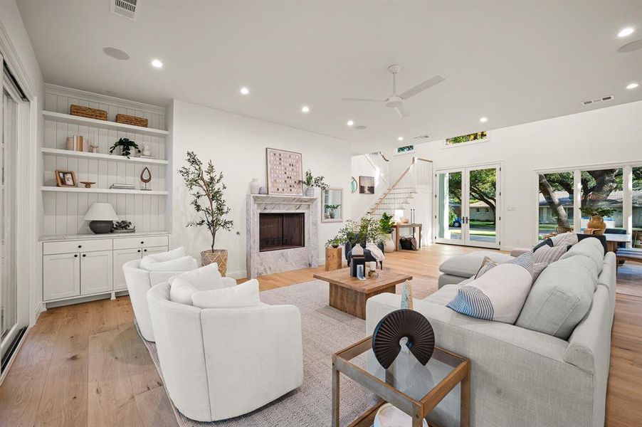 Living room with light wood-type flooring, ceiling fan, and a high end fireplace