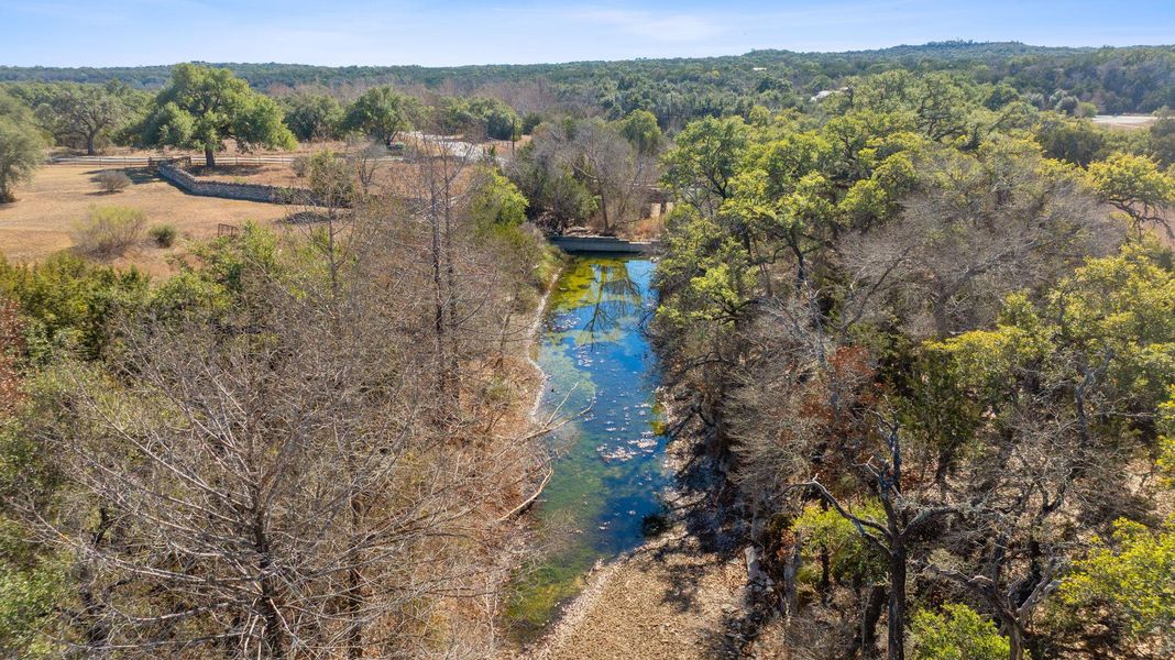 A bird's eye view of Blue Creek that borders this large lot and a tree-filled landscape
