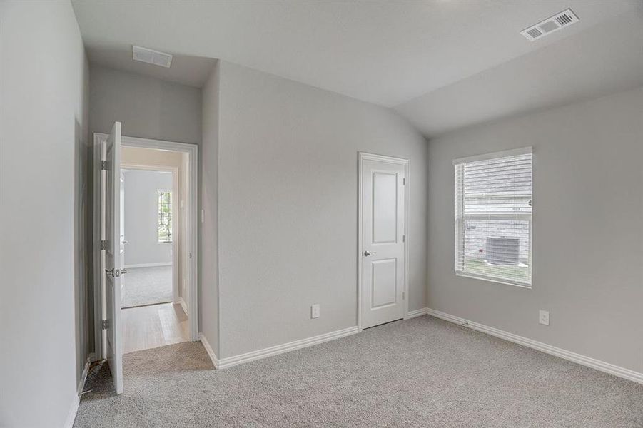 Carpeted empty room featuring vaulted ceiling