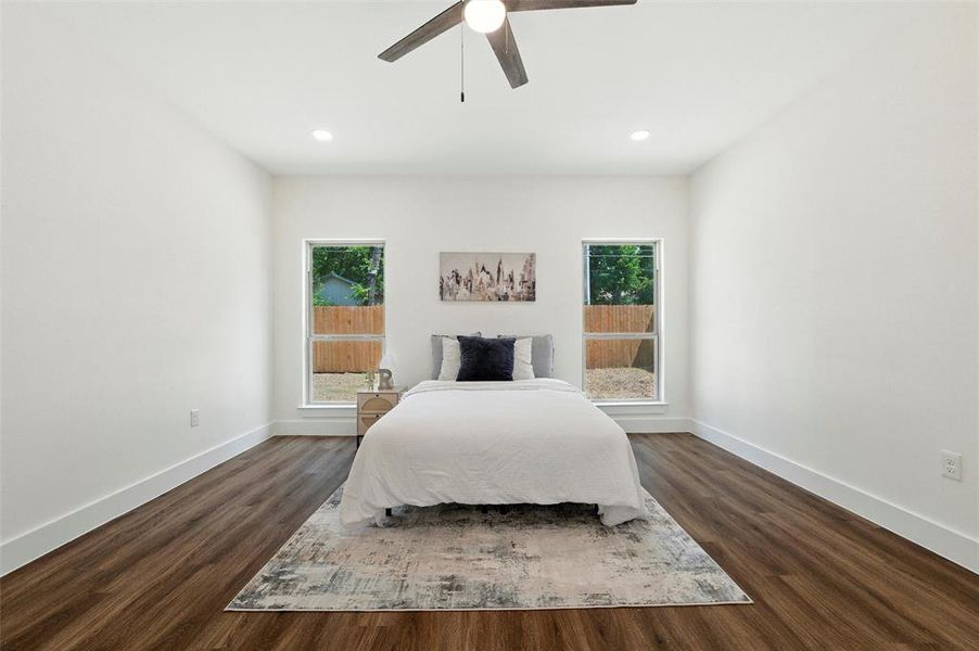 Bedroom with multiple windows, dark wood-style floors, ceiling fan, and recessed lighting