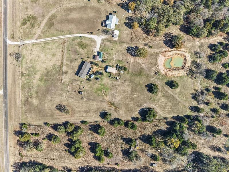 Expansive rural property featuring multiple structures, a pond, and perimeter fencing