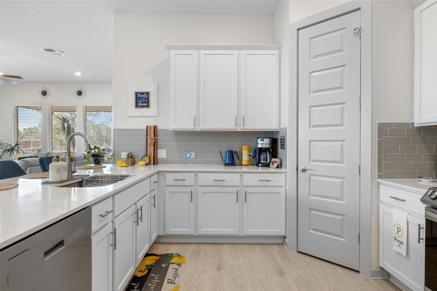 Kitchen with appliances with stainless steel finishes, white cabinets, light wood-type flooring, light stone counters, and recessed lighting Kitchen with appliances with stainless steel finishes, white cabinets, light wood-type flooring, light stone counters, and recessed lighting
