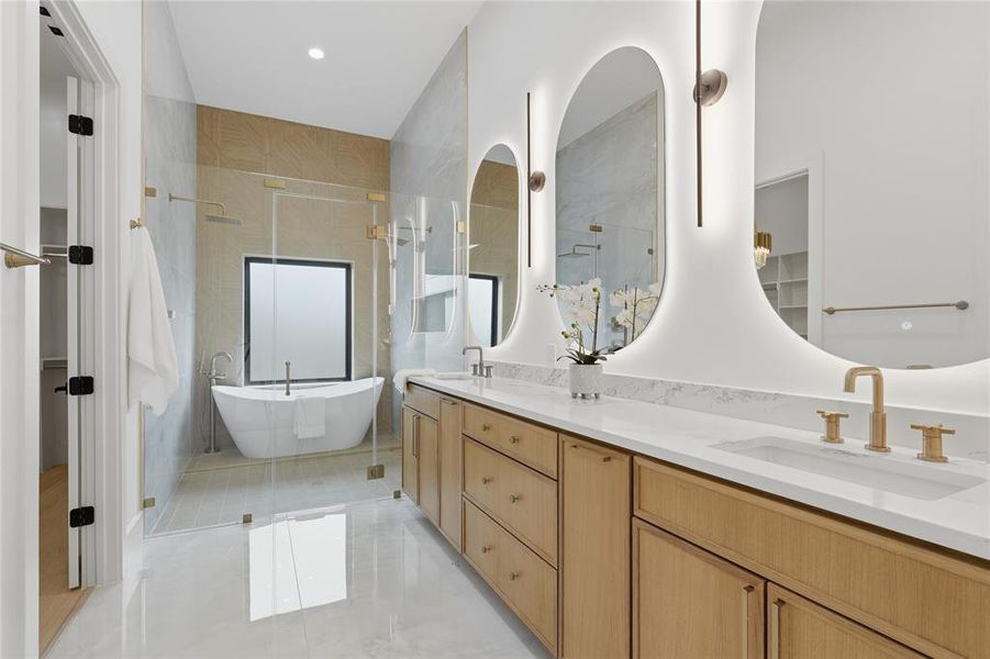 Contemporary bathroom featuring a freestanding tub, glass-enclosed shower, dual vanities with white countertops, and illuminated oval mirrors Contemporary bathroom featuring a freestanding tub, glass-enclosed shower, dual vanities with white countertops, and illuminated oval mirrors