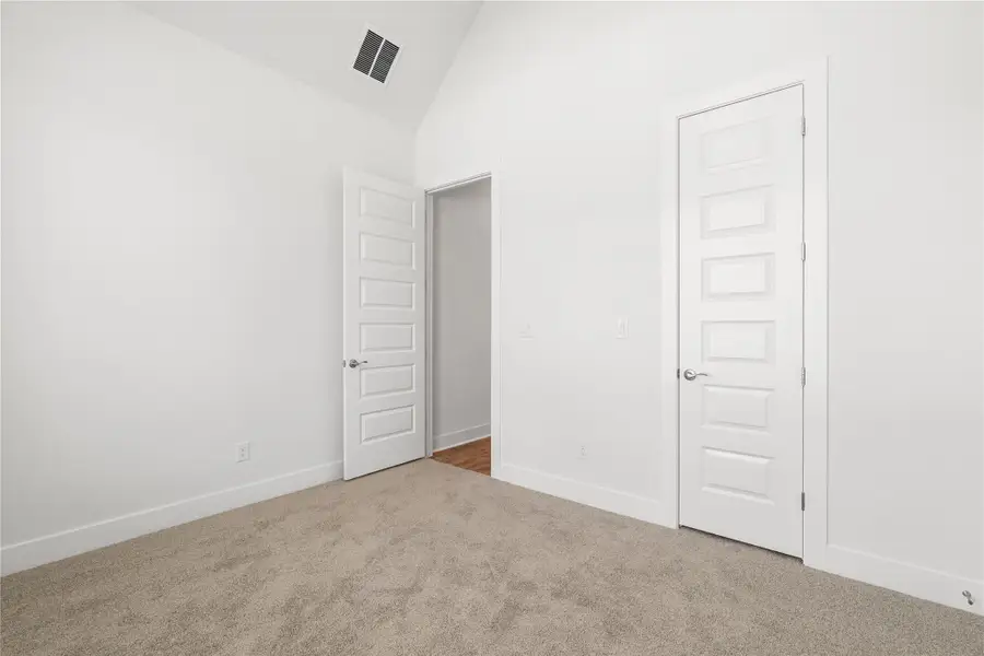 Comfortable carpeted bedroom features a vaulted ceiling and modern interior doors. Comfortable carpeted bedroom features a vaulted ceiling and modern interior doors.