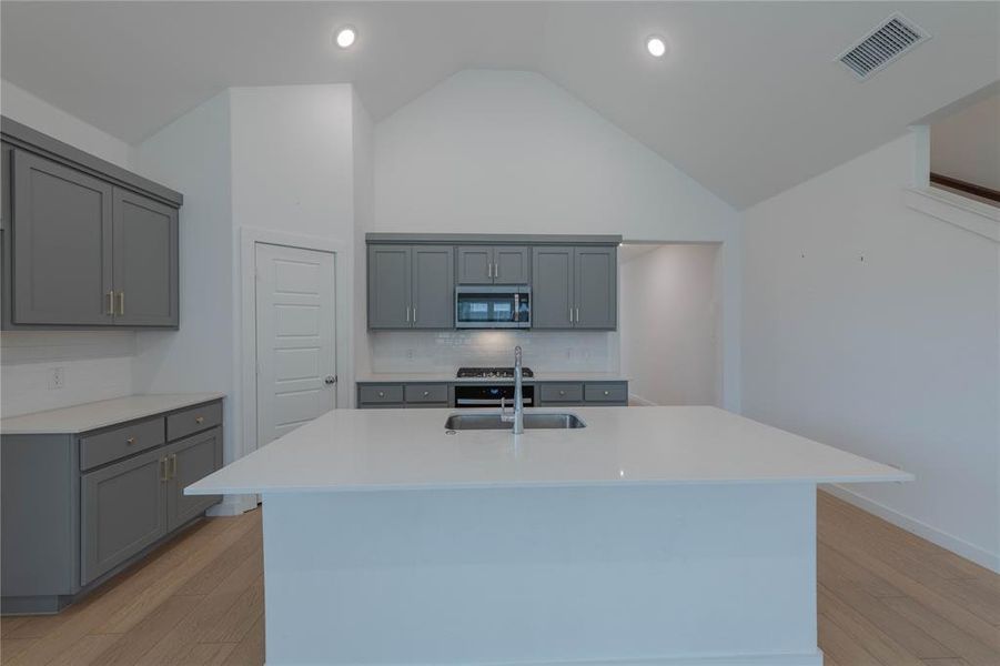 Unfurnished living room with lofted ceiling, baseboards, light wood-style floors, stairway, and recessed lighting