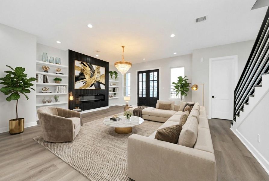 Bright open-concept living with designer finishes, featuring a chef’s kitchen with quartz island, gold accents, custom built-ins, statement fireplace, and elegant chandelier anchoring the space.