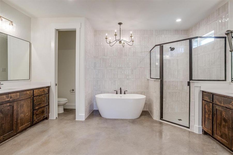 Full bathroom with vanity, concrete floors, an inviting chandelier, and tile walls