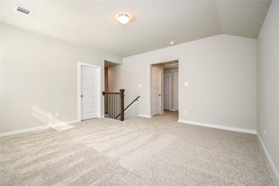 Come upstairs and relish a day of relaxation in this loft area! Ideal as an additional living space or game room, it boasts plush carpeting, high ceilings, custom paint, and windows that flood the area with abundant natural light.