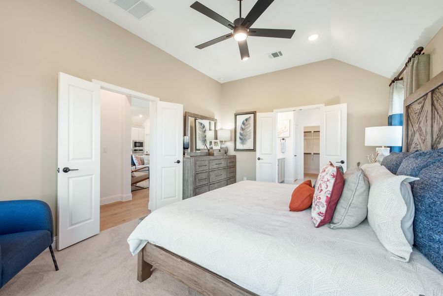 Master bedroom with vaulted ceiling, ceiling fan, barn door headboard, and walk-in closet entrance visible Master bedroom with vaulted ceiling, ceiling fan, barn door headboard, and walk-in closet entrance visible