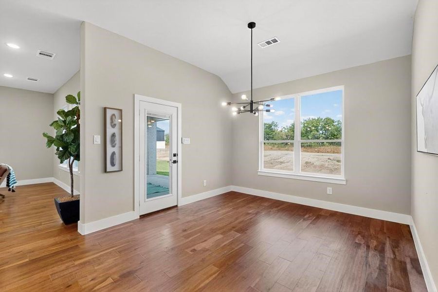 Unfurnished dining area featuring wood finished floors, vaulted ceiling, and a chandelier