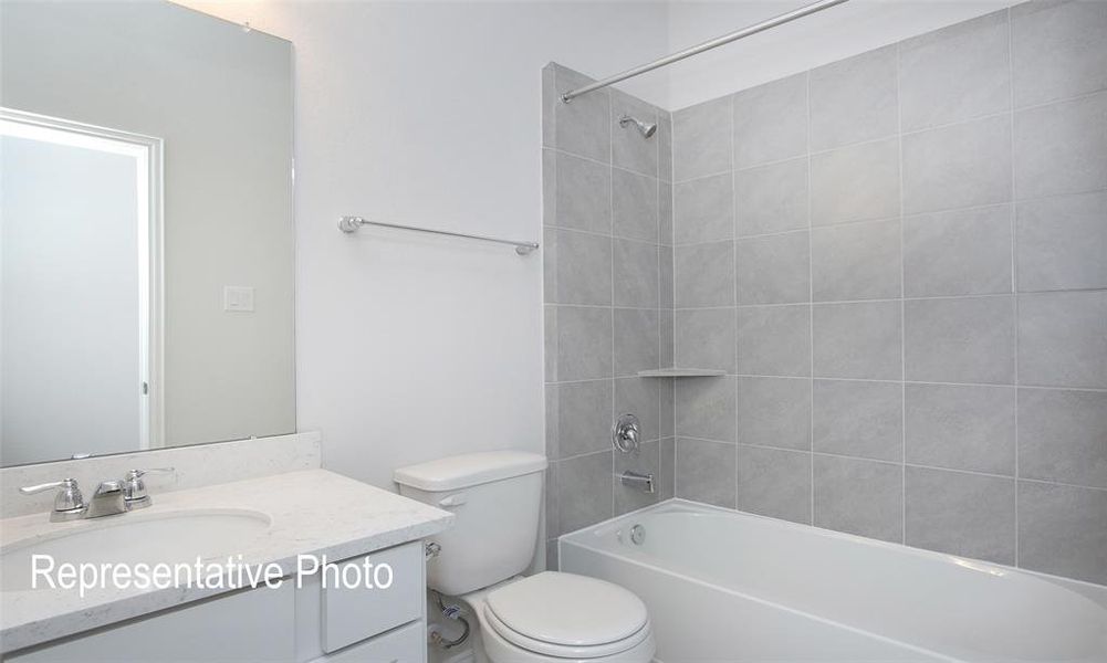 Full bathroom with tiled shower / bath combo, vanity, and toilet