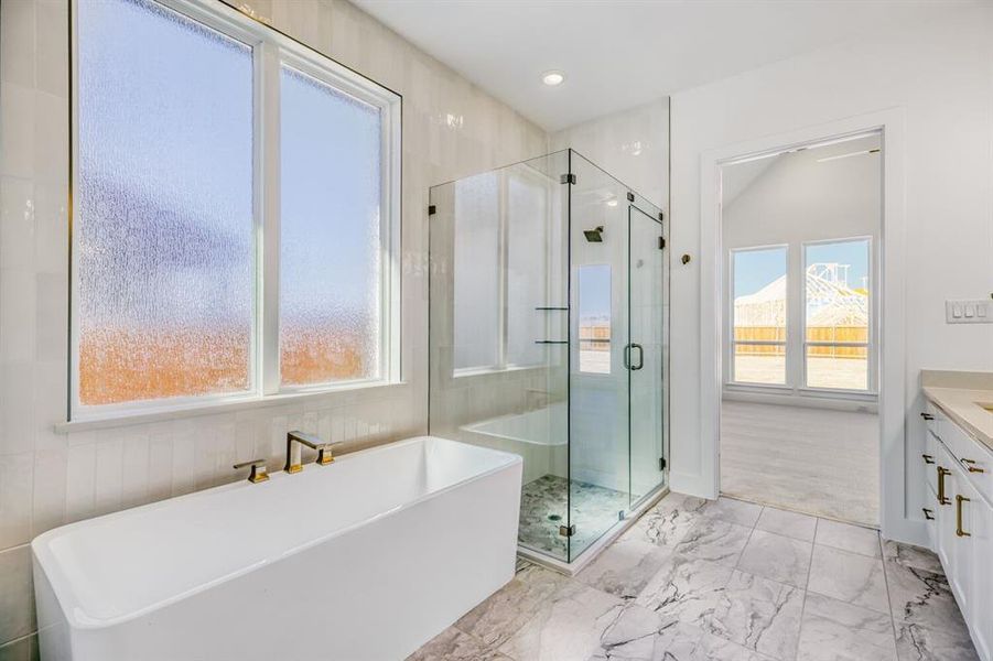 Bathroom featuring a shower stall, a soaking tub, vanity, and light marble finish floors
