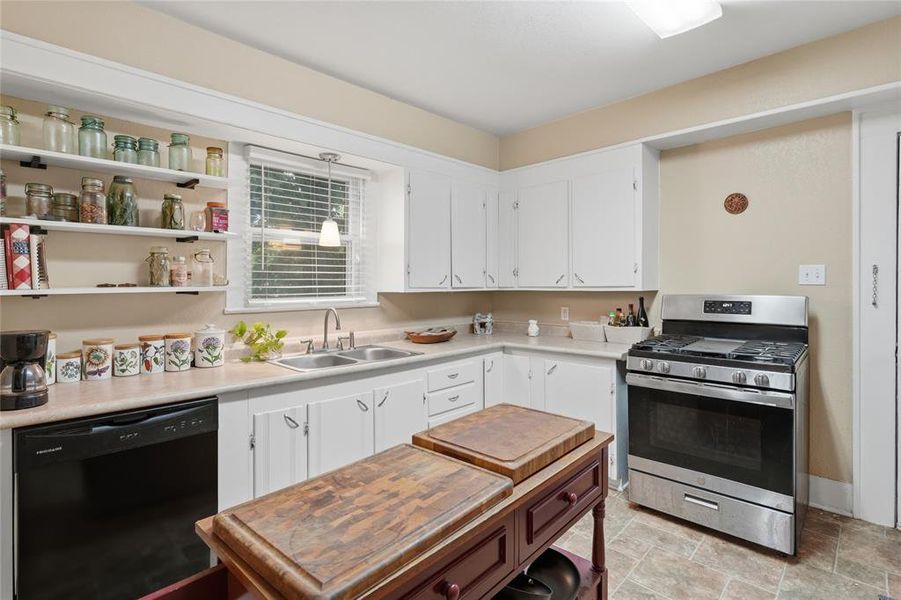 Kitchen featuring white cabinetry, a double basin stainless steel sink, a stainless steel range with a gas cooktop, and open shelving