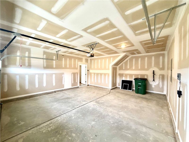 A spacious unfinished garage features concrete flo