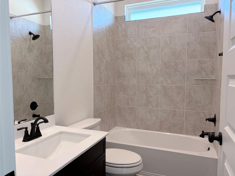 Tiled walls frame the tub shower combination in this functional bathroom space. Tiled walls frame the tub shower combination in this functional bathroom space.