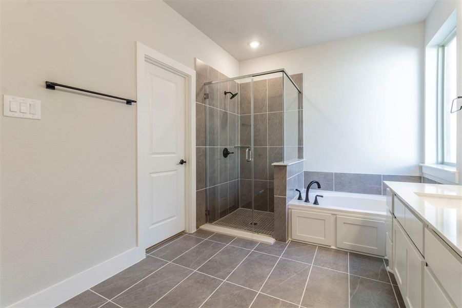 Bathroom with a bath, a shower stall, dark tile patterned floors, and vanity