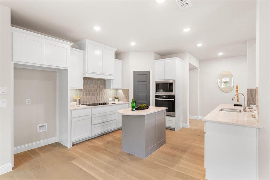 Kitchen featuring white cabinetry, tasteful backsplash, light hardwood / wood-style floors, black appliances, and sink