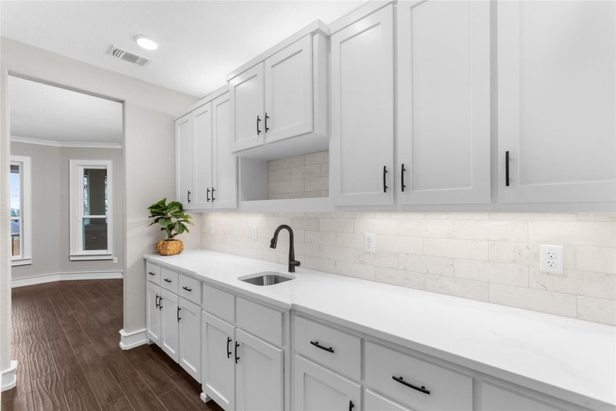 Kitchen with a sink, light countertops, tasteful backsplash, and ornamental molding Kitchen with a sink, light countertops, tasteful backsplash, and ornamental molding