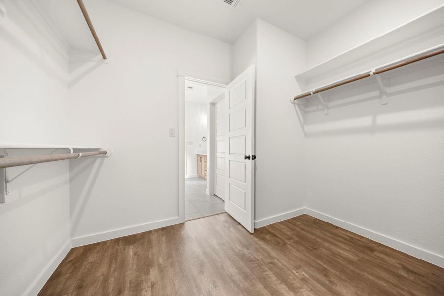 Ample hanging and shelf space within this versatile closet, featuring warm wood-look flooring.