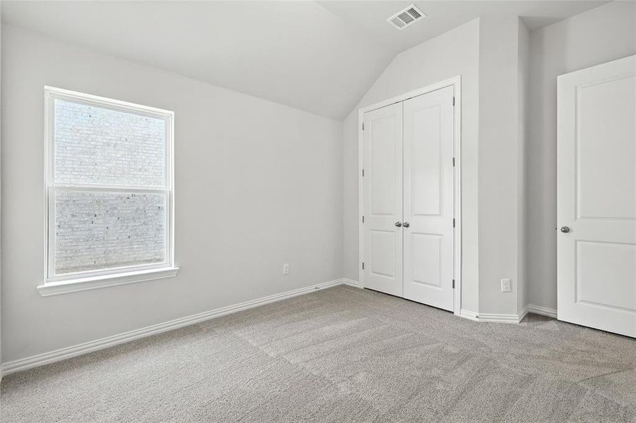 Unfurnished bedroom with light carpet, lofted ceiling, and a closet