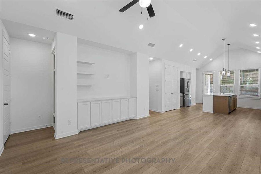 Unfurnished living room featuring light wood-type flooring, a ceiling fan, recessed lighting, and high vaulted ceiling