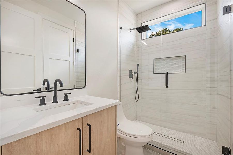 Bathroom with a shower with door, toilet, and vanity