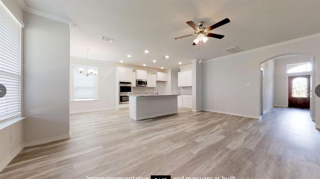 Unfurnished living room with crown molding, arched walkways, plenty of natural light, ceiling fan, and a chandelier
