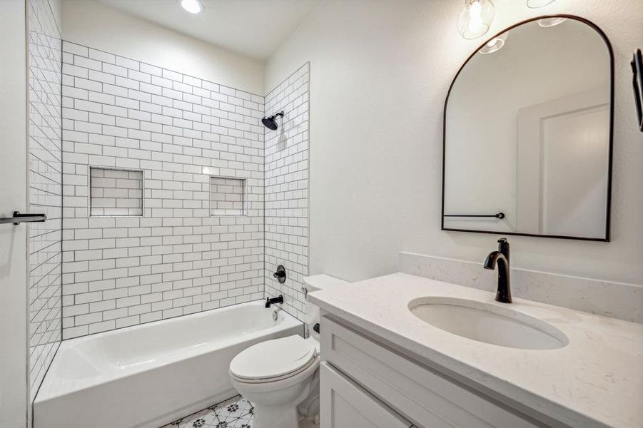 Full bathroom with vanity, toilet, tiled shower / bath, and tile patterned flooring