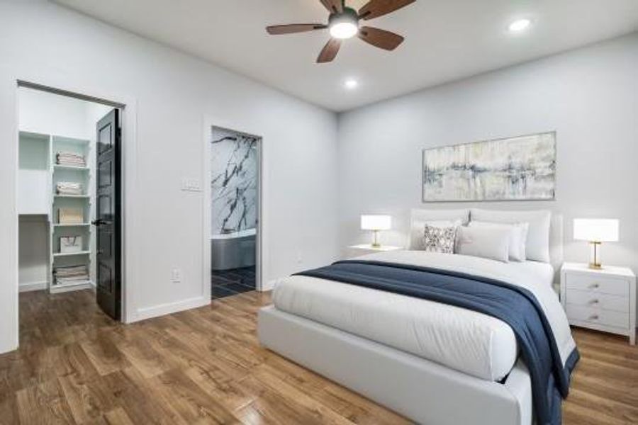 Bedroom with ensuite bath, a spacious closet, hardwood / wood-style flooring, and ceiling fan