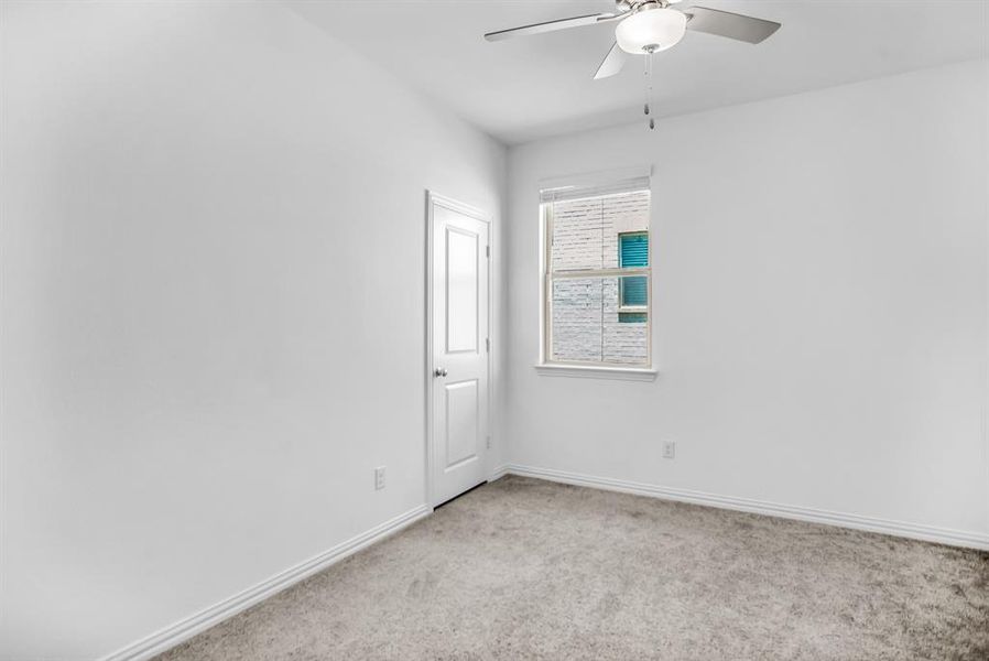 Neutral-toned carpeted room featuring a ceiling fan with integrated lighting