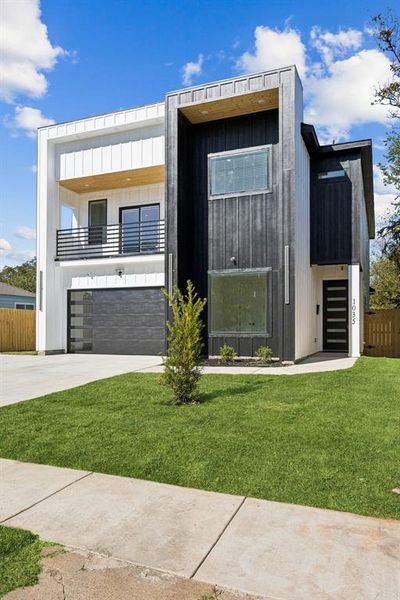 Contemporary home featuring board and batten siding, a balcony, driveway, and an attached garage