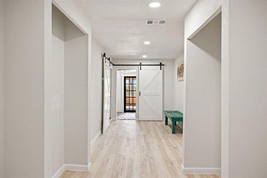 Hallway with a barn door and light wood-type flooring