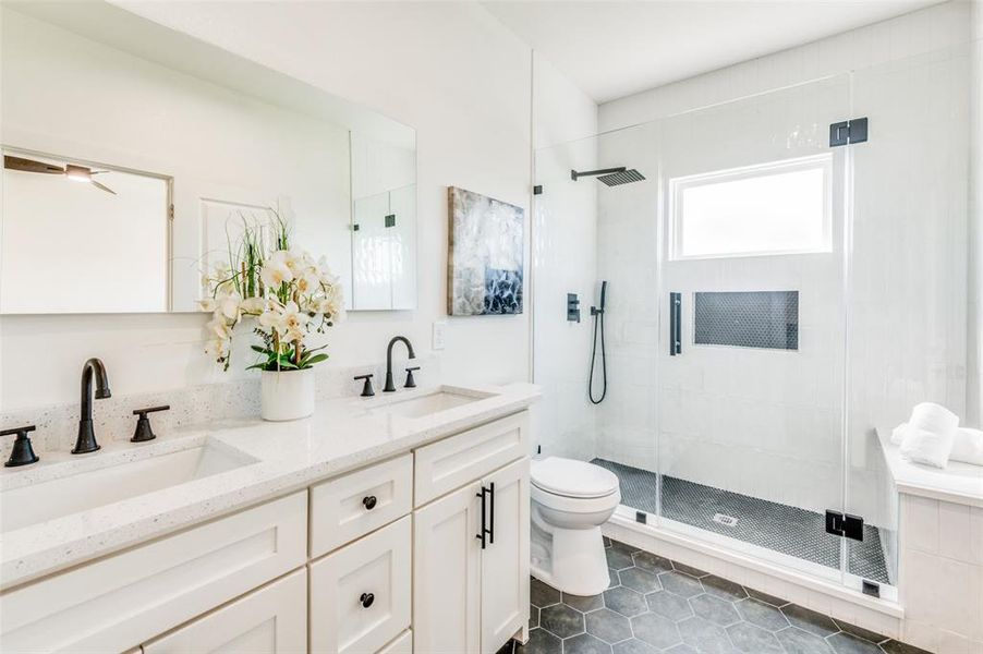 Bathroom featuring tile patterned flooring, a shower with door, vanity, and toilet