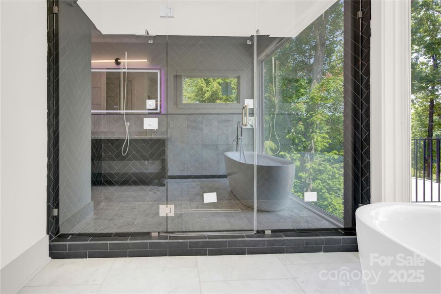 Expansive walk in shower with dual rain shower heads and seamless glass enclosure Expansive walk in shower with dual rain shower heads and seamless glass enclosure