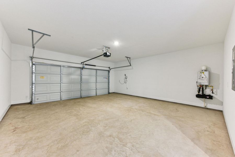 Garage featuring baseboards and a garage door opener
