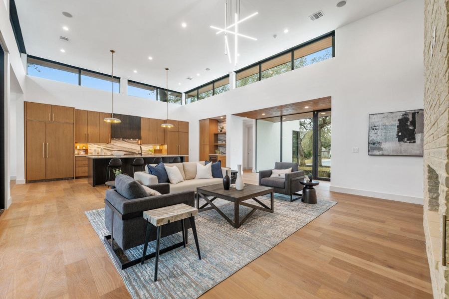 Living room with light wood-style floors, a high ceiling, and recessed lighting