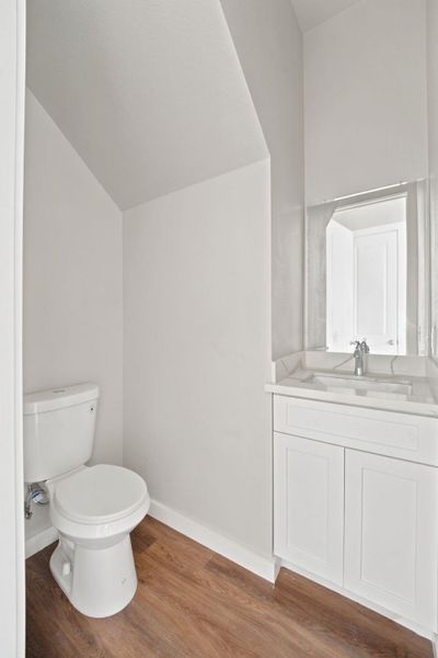 Smooth wood-look flooring and a clean white vanity define this efficient powder room.